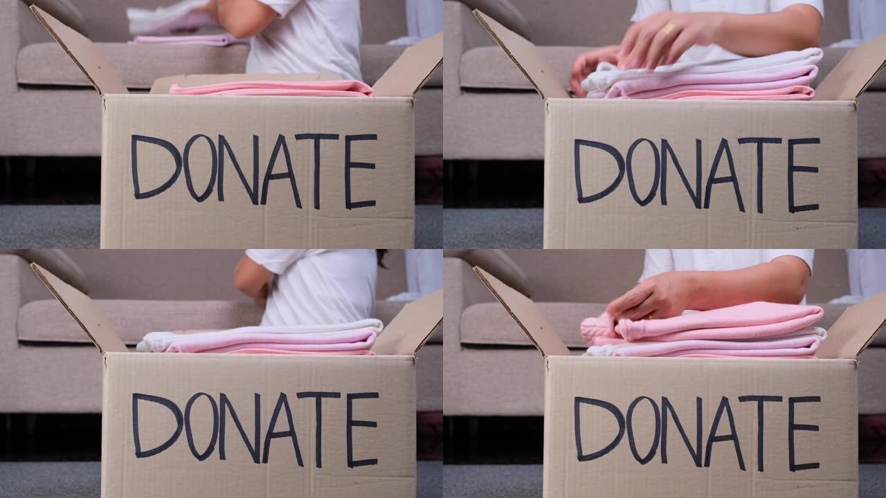 年轻女子把衣服放进家里的捐款箱里，帮助穷人。捐赠理念。