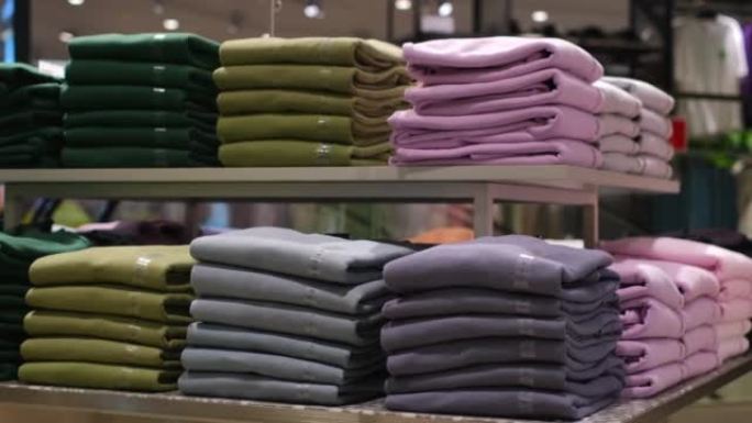 购物中心时尚商店货架上折叠服装的彩色排列，购买t恤和长袖。每天买东西穿。购物就像精神疾病