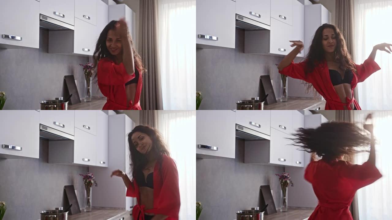 穿着红色礼服的迷人女人露出她的内衣在厨房里做性感的舞蹈动作
