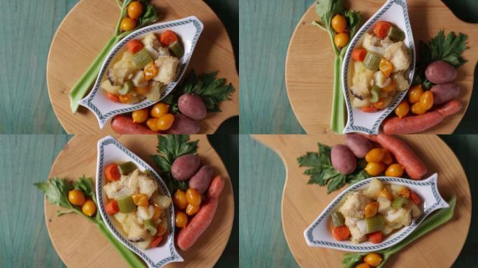 煮鳕鱼配土豆、芹菜和胡萝卜。准备烹饪的盘子的特写镜头，在绿色的木制背景上