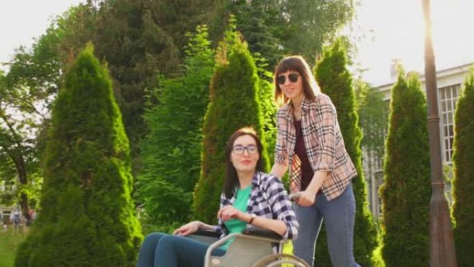 穿着衬衫的女孩卷着残疾女孩戴着眼镜和衬衫坐在轮椅上，夕阳在背景中