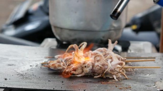 印尼街头食品销售商正在烹饪和烧烤章鱼或鱿鱼