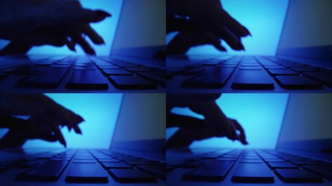 在蓝色的黑暗办公室中，女性手在笔记本电脑键盘上打字的低角度镜头。在笔记本上工作的女性。自由职业者，在