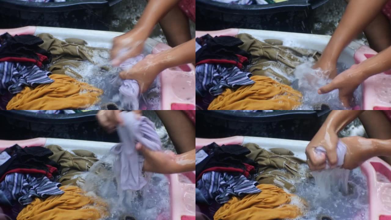 亚洲女人洗衣服。洗衣服和擦洗关闭高清视频。印度尼西亚妇女在浴室旁边洗衣服。用肥皂泡在桶里洗手