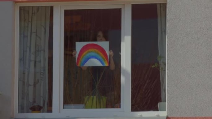 男孩在家里的窗户里拿着彩虹。彩绘标志，吸引眼球