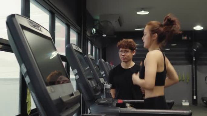 男性私人教练在健身房和一名年轻女子交谈