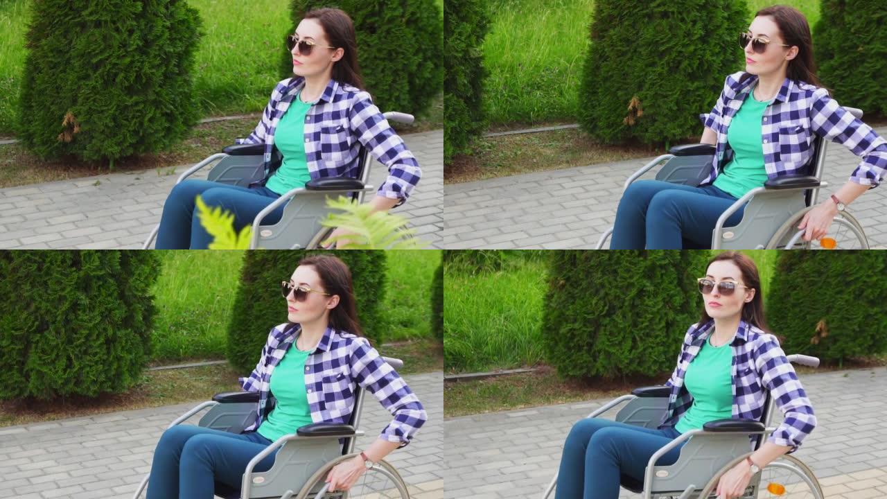 迷人的残疾女孩穿着衬衫和眼镜坐在轮椅上，在公园里慢悠悠地走着