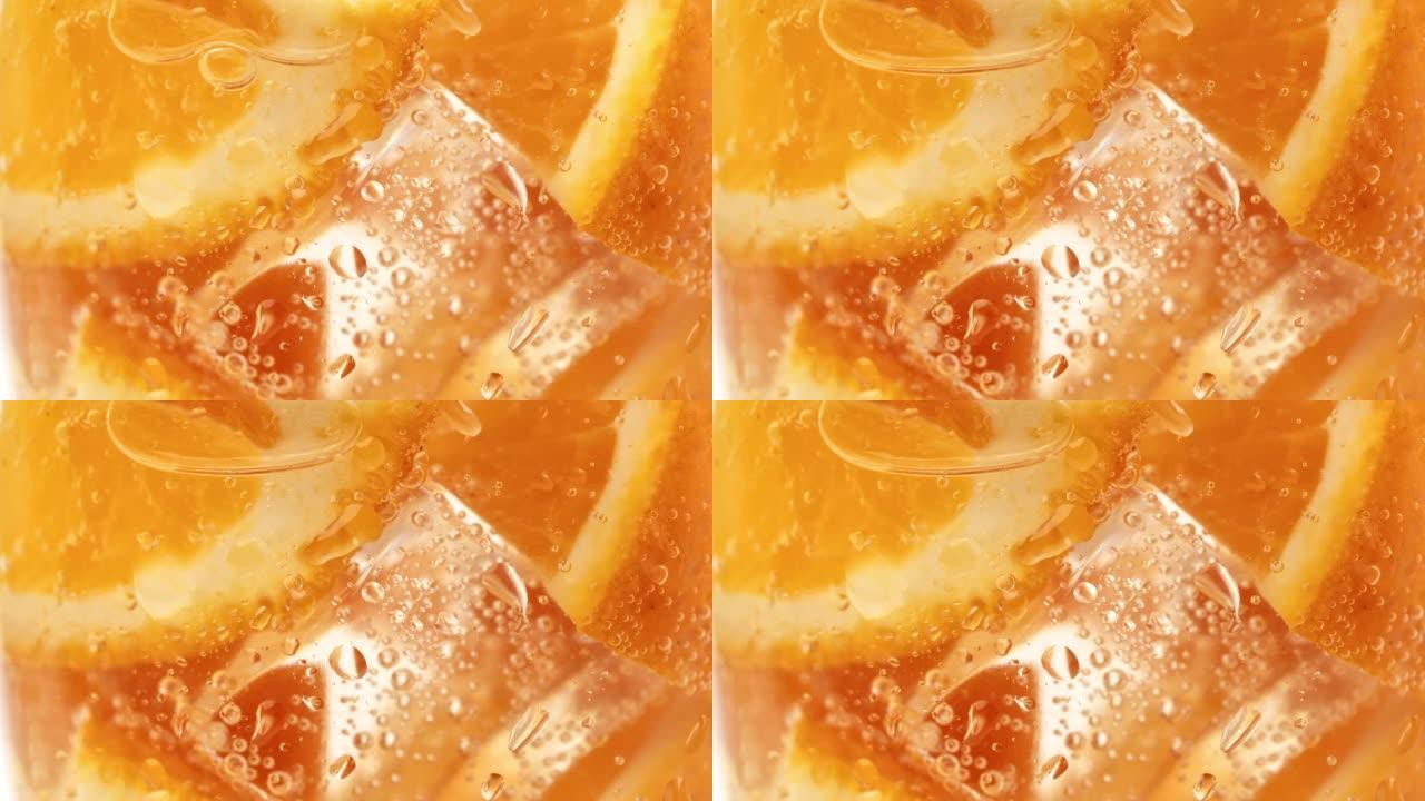 玻璃夏季鸡尾酒饮料中带冰块和碳酸碳酸水气泡的橙色碎片