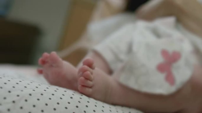 拍摄新生女婴或男婴躺在母亲的肚子上，移动她可爱的小脚。妈妈和刚出生的孩子在医院玩他柔软的腿。父母在床
