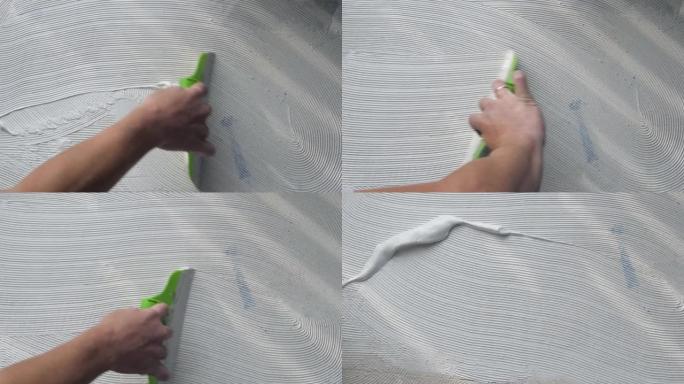 工人在粘贴乙烯基层压砖之前使用刮刀在地板上涂抹胶水