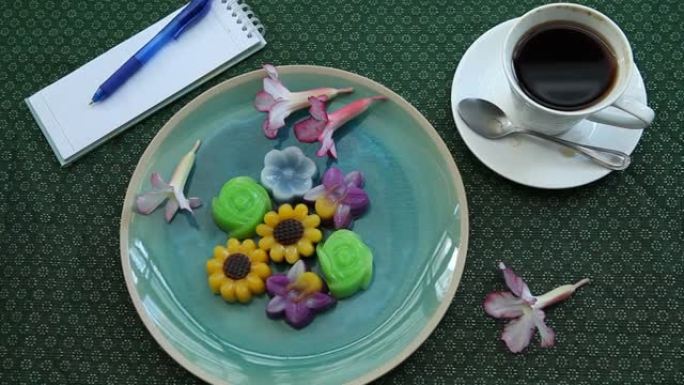 漂亮的花形甜点，配有热咖啡饮料和笔记本，背景