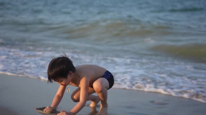 日落时，亚洲男孩在海滩上享受和玩海和沙滩
