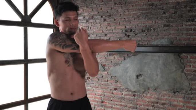 健身男子在伸展废弃仓库锻炼。