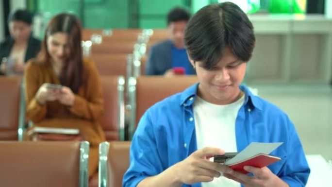 年轻的亚洲男子使用手机上网，并在等待机场登机口办理登机手续时也持有护照和登机牌