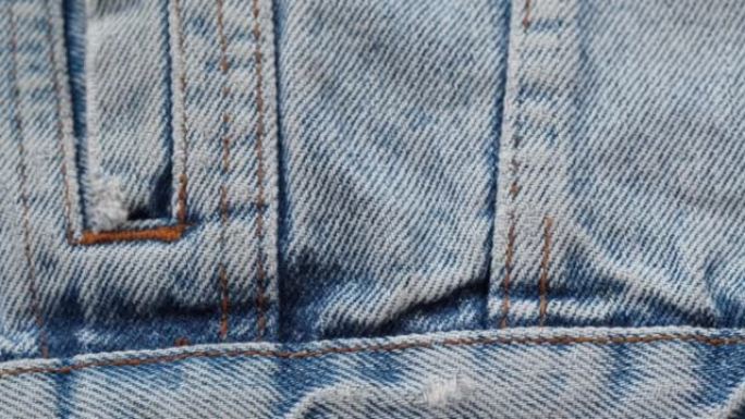 蓝色牛仔裤面料特写。牛仔布纹理，抽象背景。裁缝工业和服装概念，手工缝制。纺织材料