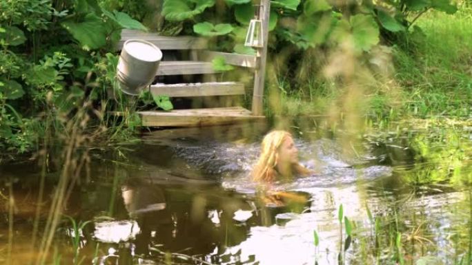 一个苗条的年轻女子在芦苇和大鱼之间的池塘里游泳