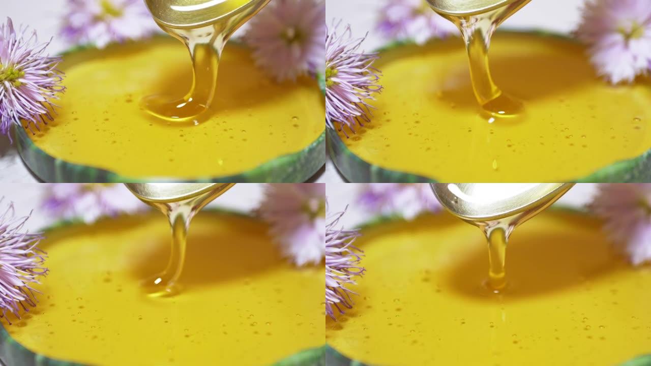 透明的蜂蜜从勺子倒入盖子，碗中。特写。缩放