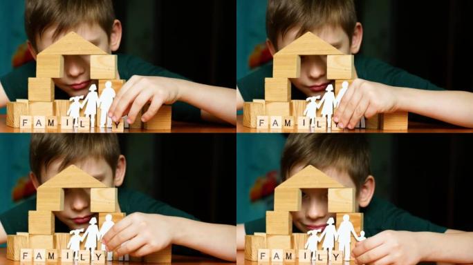 快乐的高加索男孩6-7岁玩立方体，盖房子。带孩子的剪纸家庭，用立方体刻字家庭。孩子扮演家庭梦想。选择