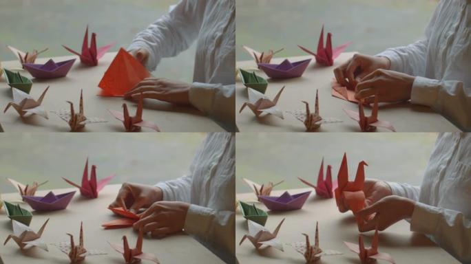 亚洲女人用手在窗边做折纸。折纸鹤等造型工艺美术作品