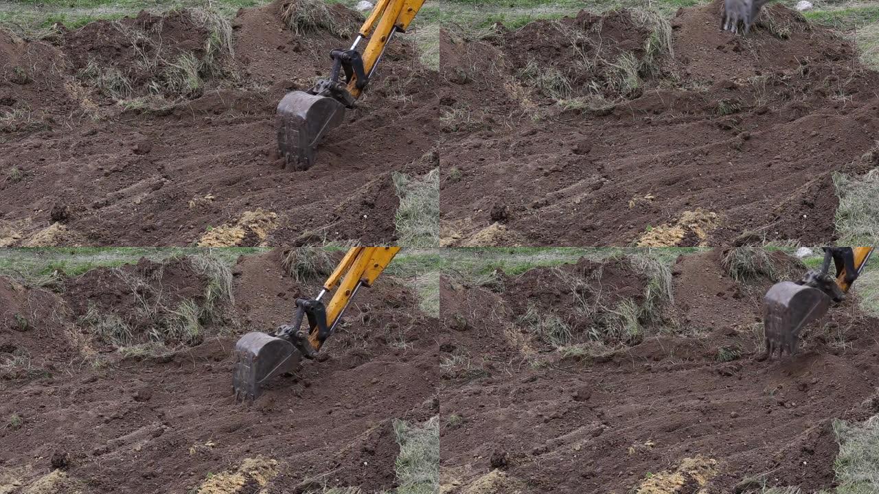 挖掘机铲斗铲去除了顶层的土壤并将其清理起来