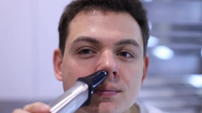 用舒适的电动修剪器帮助男人去除鼻毛的特写脸