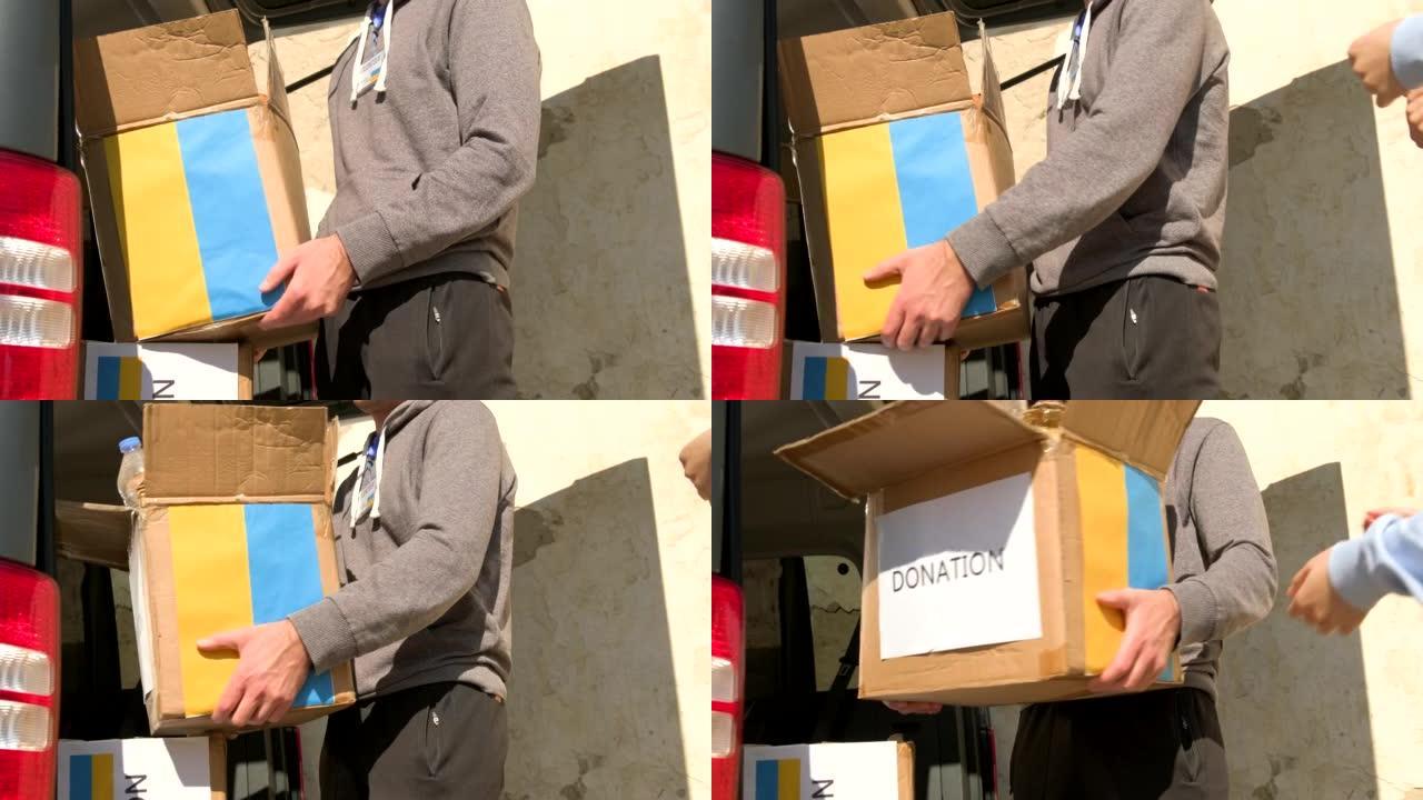 年轻男子志愿者将食物的捐款箱转移给年轻女子志愿者，以便他们可以在难民中分发。