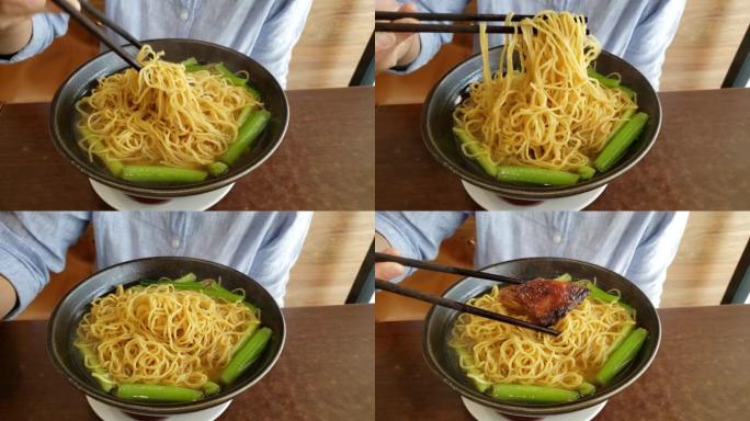 用筷子将新鲜的一碗中国鸡蛋面轻轻混合在淡汤中