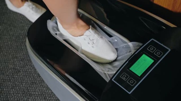 自动热收缩鞋套覆膜机。特写。机器自动将鞋套涂在病人的鞋子上