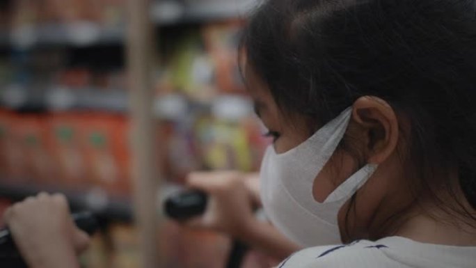 超市里戴口罩推手推车的亚洲女童