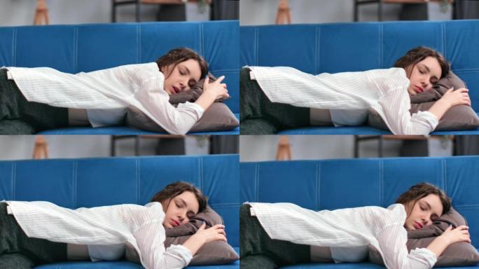 疲惫的黑发女人摔倒在舒适的靠垫蓝色沙发上，精神疼痛过度劳累