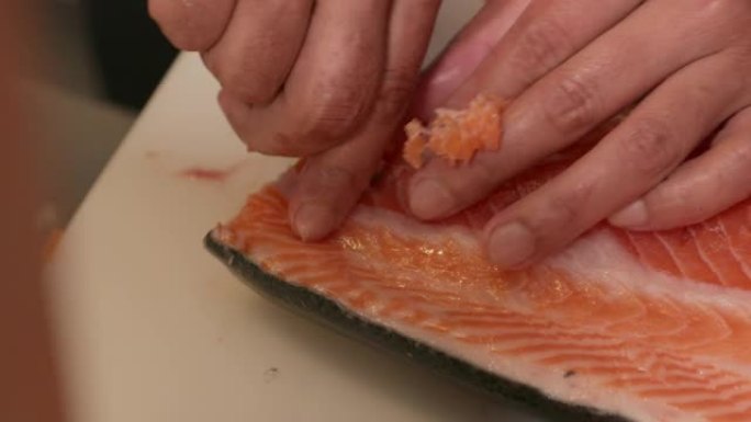 使用镊子从未煮熟的三文鱼肉中去除针骨