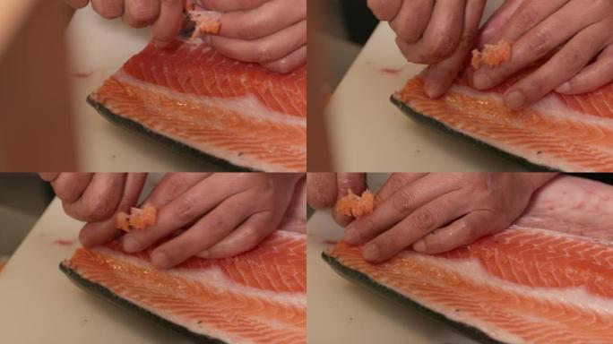 使用镊子从未煮熟的三文鱼肉中去除针骨