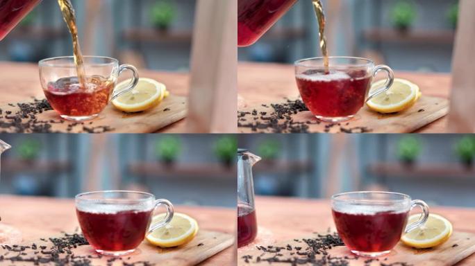 特写镜头将罐茶壶中的新鲜热香气红茶倒入木制桌子上的玻璃杯中