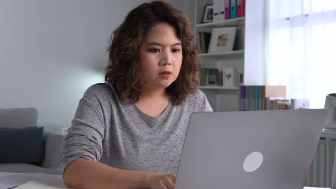 感到疲倦和压力。年轻的亚洲妇女坐在办公室里用笔记本电脑工作时，思想深处疲惫不堪。