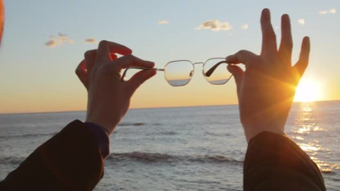 展望未来，日出海洋中女孩手持眼镜的概念