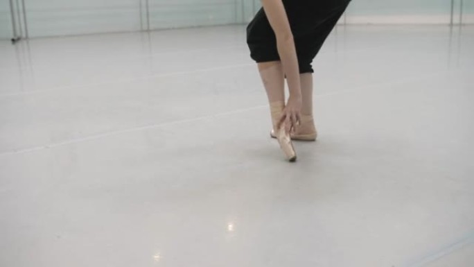 一名芭蕾舞演员在排练室里伸腿。芭蕾舞排练。
