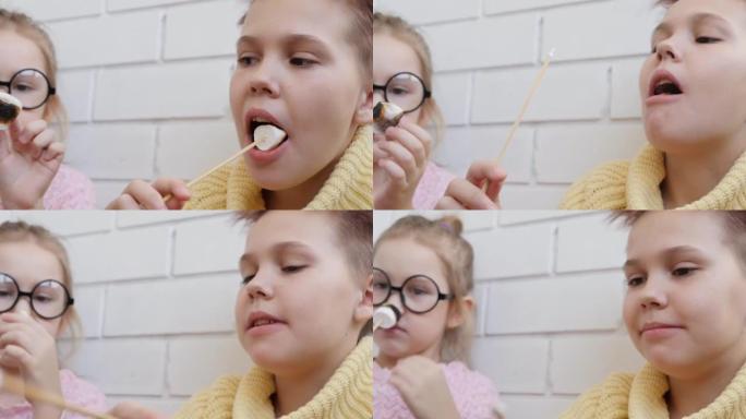 两个十几岁的女孩在木棍上吃油炸棉花糖