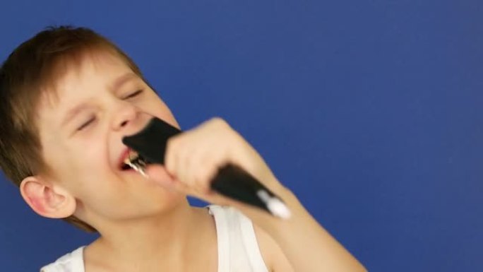 一个7-8岁快乐的高加索男孩的肖像在浴室里唱歌，在蓝色背景上梳理。孩子在浴室里欢快地唱歌。早上好，孩