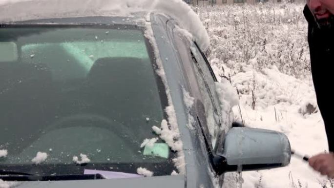 男子用冰雪清洁汽车挡风玻璃