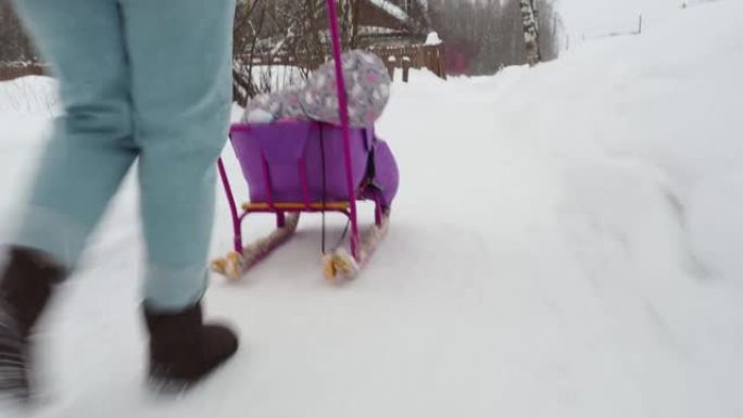 一个女孩在雪中的雪橇上背着一个熟睡的孩子