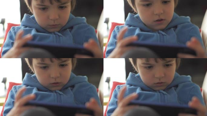 孩子坐在沙发上在家打电话玩游戏。男孩在手机上玩电子游戏。学龄前儿童在沙发上玩电子游戏智能手机。儿童使