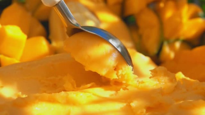 勺子的特写慢慢舀冷冻黄色芒果冰淇淋冰淇淋