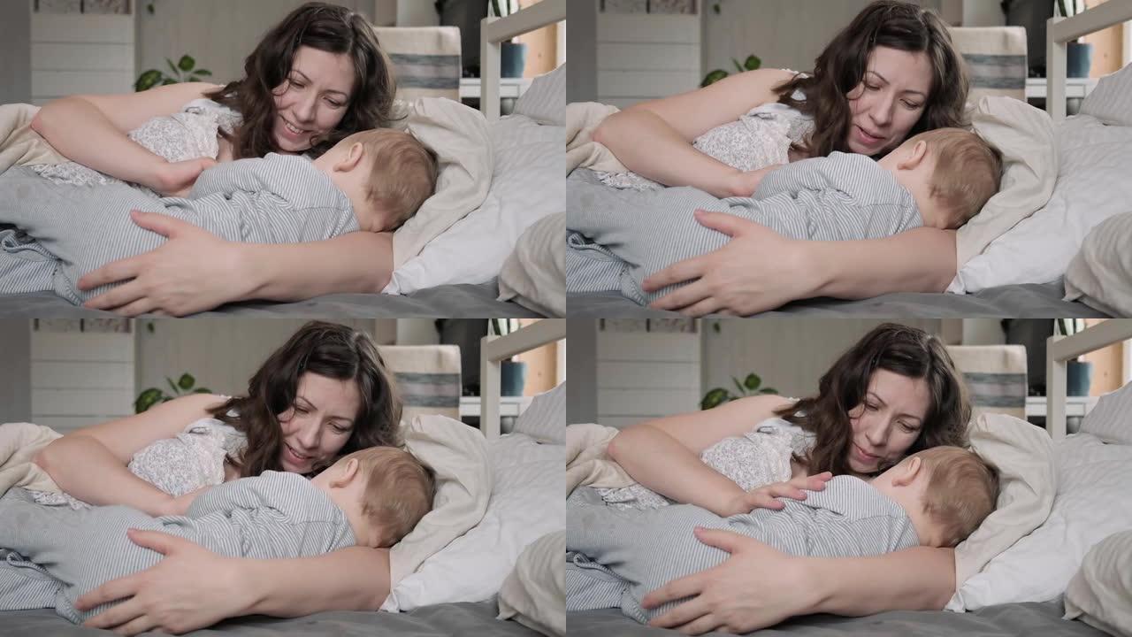 一位穿着睡衣的白人黑发母亲在床上放松时母乳喂养她的小新生儿。带着婴儿睡在家里的年轻女子。同床概念。婴