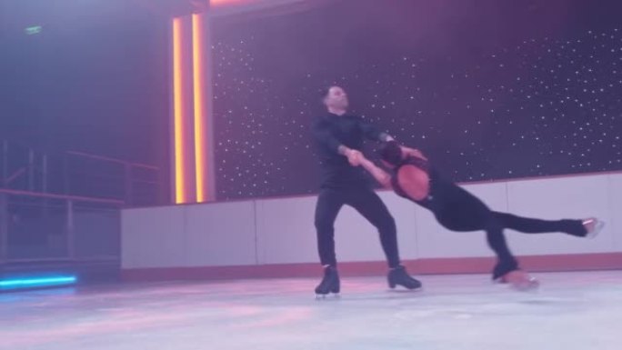 一对花样滑冰运动员在溜冰场上旋转，女人进入死亡螺旋，在空中盘旋，平行于两腿结冰，男人用手扶着她。花样