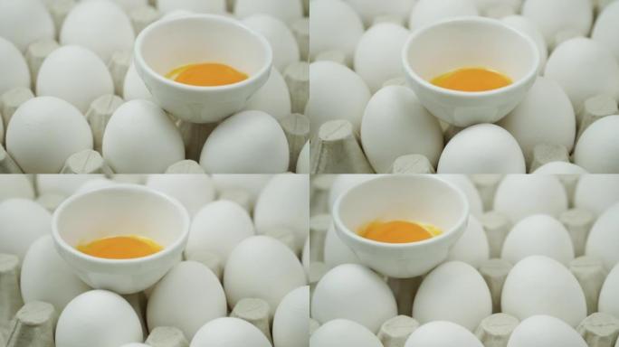 纸箱蛋盒中许多白色鸡蛋之间的破碎鸡蛋旋转