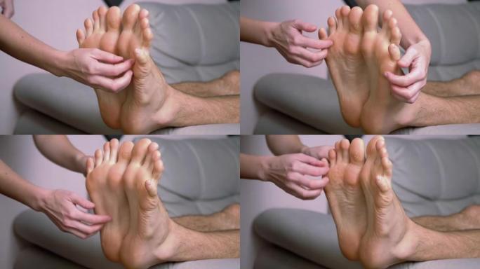 女人的手挠男人的光脚，脚趾，在沙发上伸展。时间流逝