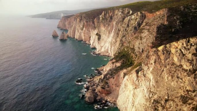 希腊扎金索斯爱奥尼亚海海岸的空中无人机视图。岩石悬崖，植被，蓝色的水。日落