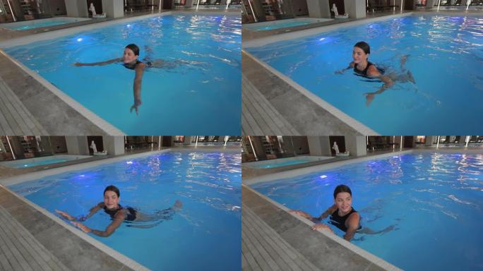 可爱的女人在豪华酒店的游泳池里游泳