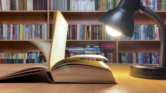 在经典图书馆的灯下，风在木桌上翻页和闭页。书架。