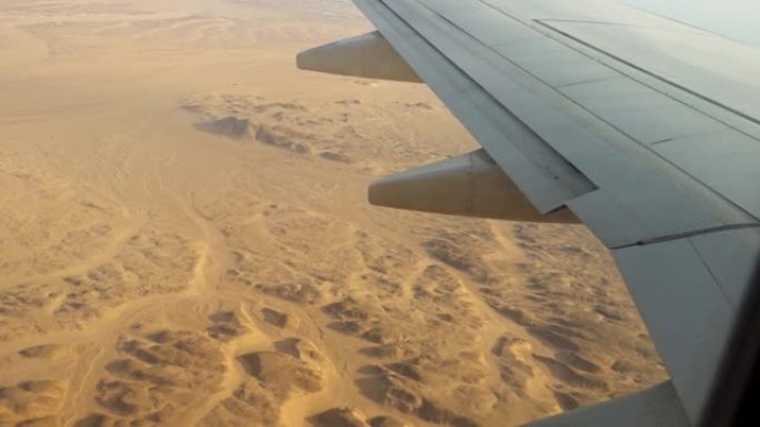 飞机飞越沙漠，从飞机机翼的舷窗和襟翼上的视野。
